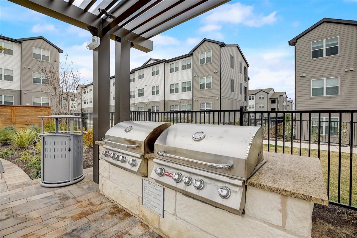 Outdoor grilling area with stainless gas grills, stone counters, and covered pergola for cookouts.